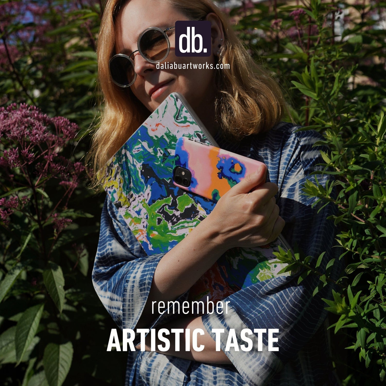 DaliaBuArtworks creator with her artworks printed on MacBook and phone cases.