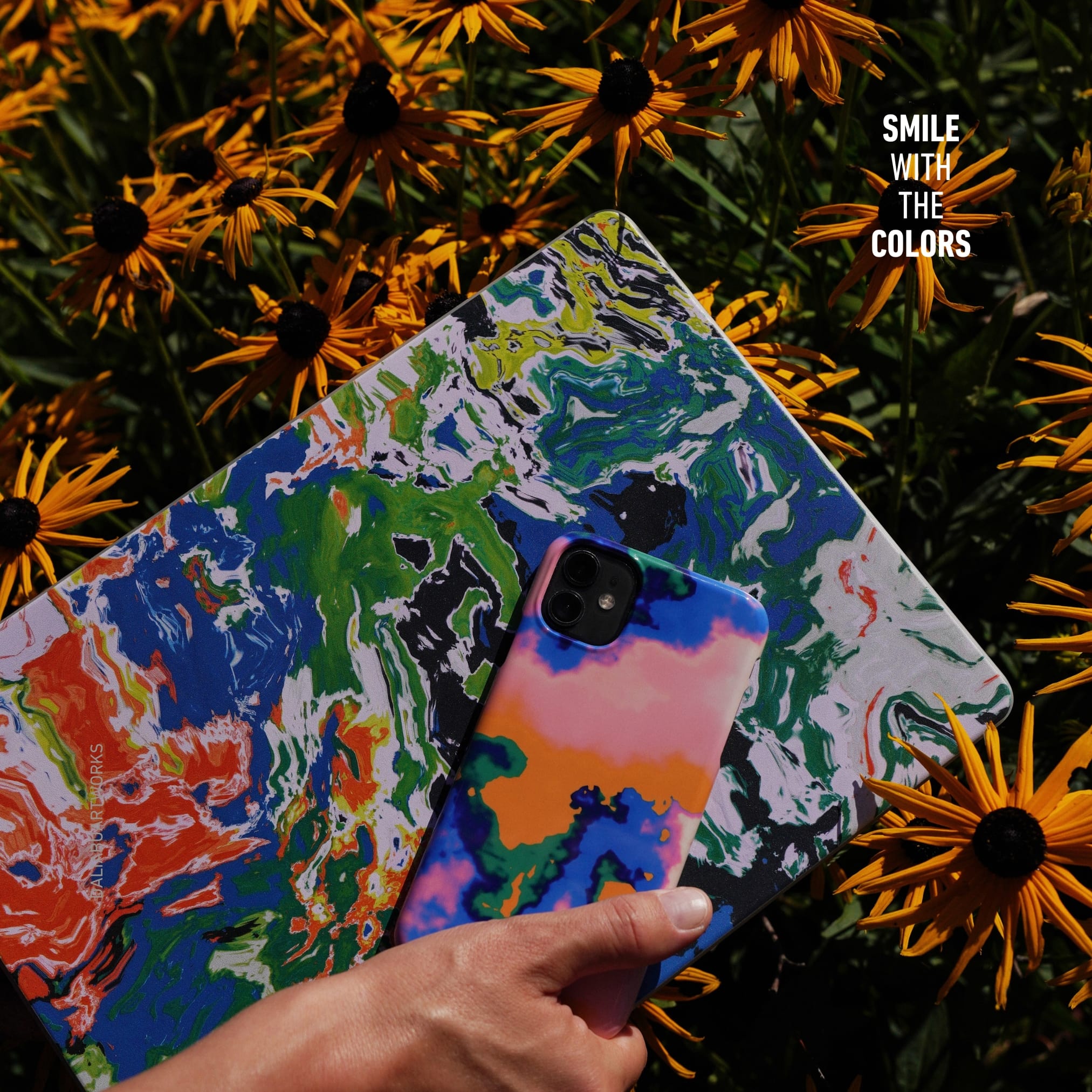 Colorful phone case with abstract design held by a hand, surrounded by yellow flowers with 'Smile with the Colors' text.